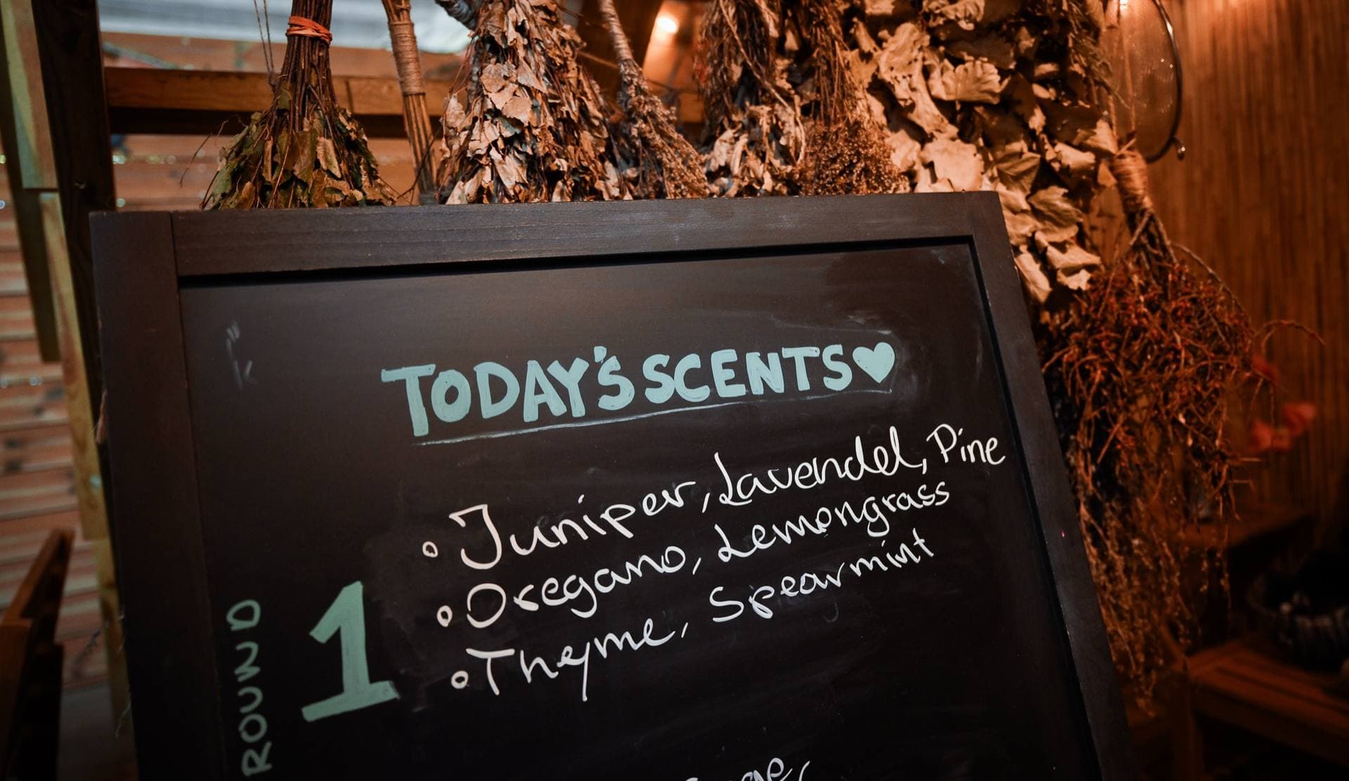 The chalkboard with today's scents for each round, under dried herbs